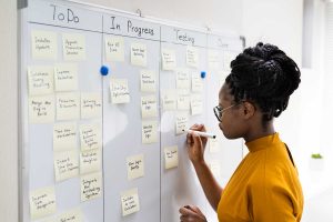 kvinna som skriver på en kanban tavla