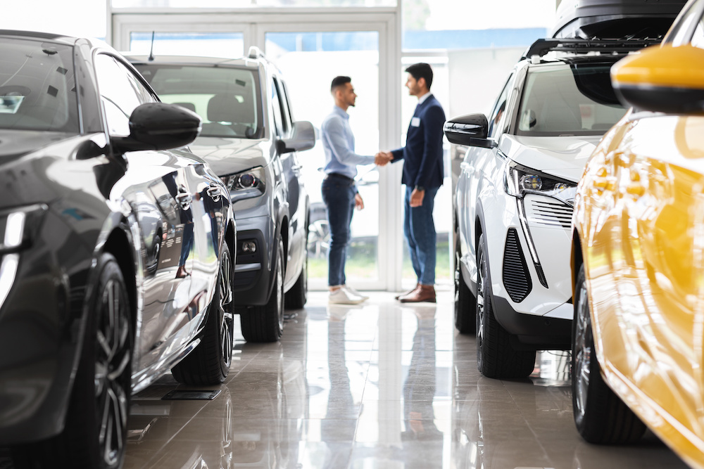 Köpare och säljare skakar hand hos en bilhandlare